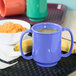 A peacock blue GET Tritan plastic mug with two handles next to a bowl of porridge and a banana.