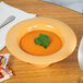 A bowl of soup in a Tropical Yellow melamine bowl with a leaf on top.