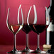 Three Stolzle Classic burgundy wine glasses filled with red wine.