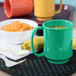 A tray with a green GET Rainforest Green Tritan mug, a bowl of food, and a banana on it.