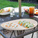 A Manila oval melamine platter with food on a table outdoors.
