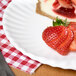 A plate of strawberries and cheesecake on an American Metalcraft round melamine plate.