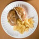An American Metalcraft white melamine plate with a sandwich and chips on it.