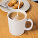A white GET Tritan mug filled with coffee and milk on a table with croissants.