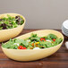 Two GET Dijon melamine bowls filled with salads on a table.