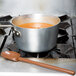 A brown Mercer Culinary Hell's Tools high temperature mixing spoon stirring soup in a pot.