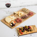 A GET faux oak wood melamine display tray with different types of cheese and meat on it.