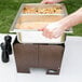 A person preparing food in a Sterno Copper Vein fold away chafer with clear dome cover and half size pans on a table.