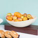 A GET Osslo melamine bowl filled with apples and oranges on a table.