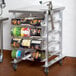 A Regency metal cart with a stainless steel top and can racks holding #10 and #5 cans.
