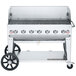 A Crown Verity natural gas outdoor grill on wheels with a wind guard.