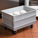 A gray fiberglass MFG Tray dough proofing box dolly with white trays on it.
