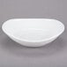 A Libbey Infinity bright white porcelain oval bowl with a small rim on a gray surface.