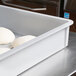 A gray MFG Tray fiberglass dough proofing box on a counter filled with dough.