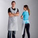 A man and woman standing in front of each other, wearing white Choice plastic aprons.