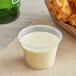 A clear plastic Choice souffle cup filled with white sauce next to fried chicken wings.