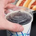 A hand holding a Choice translucent plastic lid on a plastic cup with a straw.