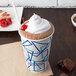 A Choice 16 oz. paper cold cup of hot chocolate with whipped cream and a cherry.