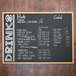 A black Aarco chalk menu board with white writing on a counter.
