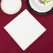 A white Creative Converting paper dinner napkin next to a white cake.