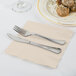 A knife and fork on an ivory 1/4 fold luncheon napkin.