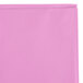 A folded pink plastic table cover in a plastic bag with a white background.