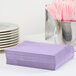 A stack of Creative Converting Luscious Lavender paper napkins on a table.
