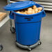 A blue Rubbermaid BRUTE trash can full of potatoes.