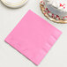 A Candy Pink Creative Converting paper dinner napkin next to a cake.