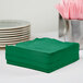A stack of Creative Converting emerald green luncheon napkins.