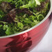 A Vollrath Dazzle Red metal bowl filled with green and red lettuce.