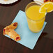 A glass of orange juice next to pastries with a pastel blue Creative Converting beverage napkin.