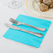 A knife and fork on a Bermuda blue Creative Converting luncheon napkin.