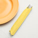 A fork in a Creative Converting Mimosa Yellow 3-ply paper dinner napkin.