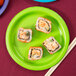 A Creative Converting Fresh Lime Green paper plate with a sushi roll on it.