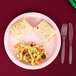 A Classic Pink paper plate with pasta and bread on a table.