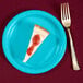 A piece of cheesecake on a Creative Converting Bermuda Blue paper plate with a fork.