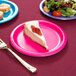 A slice of cheesecake on a Creative Converting hot magenta pink paper plate next to a fork.