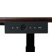 A close up of the Luxor Dark Walnut Electric Adjustable Standing Desk remote control on a wood surface.