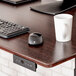 A white mug and a computer mouse on a Luxor Dark Walnut electric standing desk.