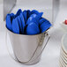 A bucket filled with Creative Converting cobalt blue plastic spoons.