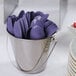 A bucket filled with purple spoons and forks.