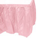 A pink plastic table skirt with a white border.