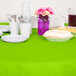 A table with a Fresh Lime Green OctyRound table cover and plates and utensils on it.