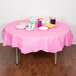 A table with a Creative Converting candy pink OctyRound table cover, plates, and cups with food on it.