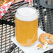 A WNA Comet clear plastic beer can filled with beer and a pretzel on a table.