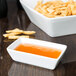 A white rectangular Libbey porcelain sauce bowl with orange liquid in it.