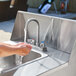 A person washing their hands in a Crown Verity portable hand sink.