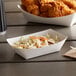 A white customizable paper food tray with coleslaw and chicken wings inside.