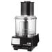 A black Waring food processor with clear container and white lid.